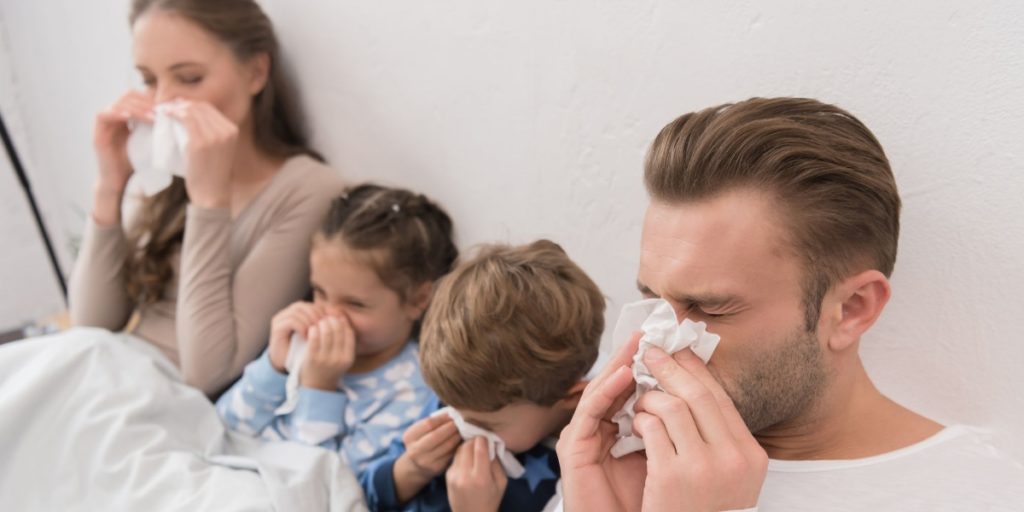 A family in bed, all suffering with illness