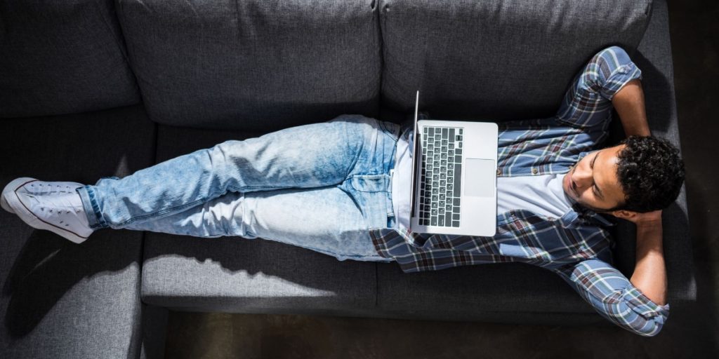 Man relaxing on the sofa with his laptop, no doubt wondering how to be productive when you work from home?