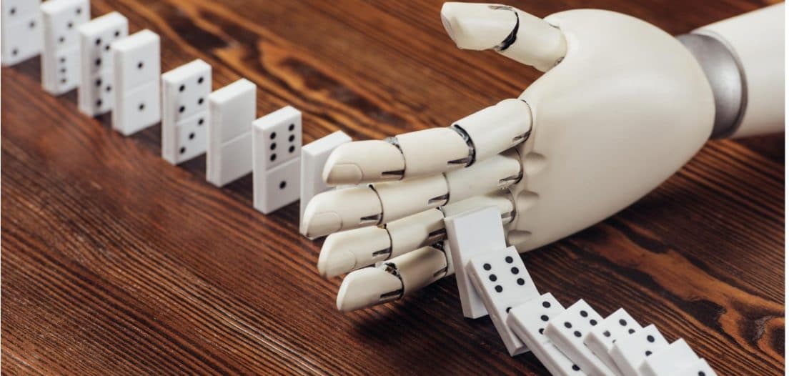 A robot hand stops a sequence of dominoes falling down