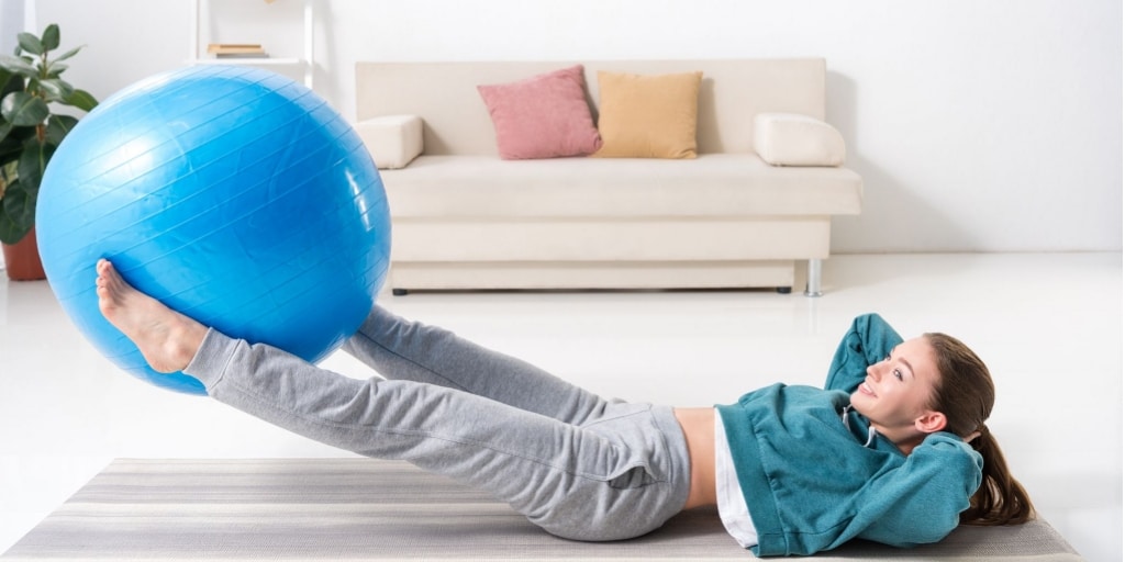 A lady working out at home with an exercise ball