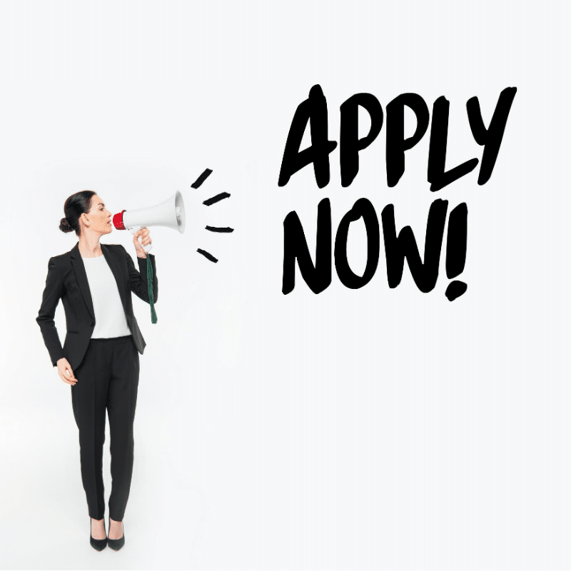 Lady wearing a black suit and white top shouting into a loud haler APPLY NOW!