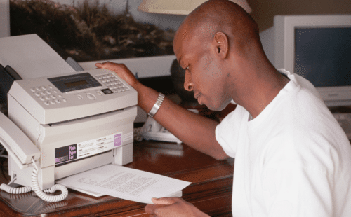 Man operating a fax machine, the ultimate recruitment technology in the 1990s