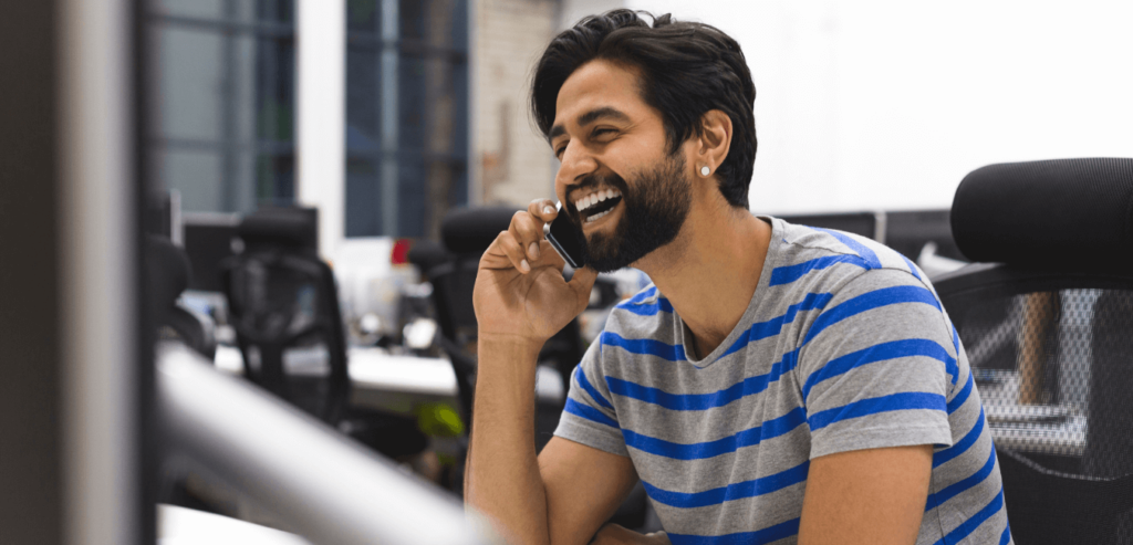 The only guy left in the office laughing while talking on his mobile phone