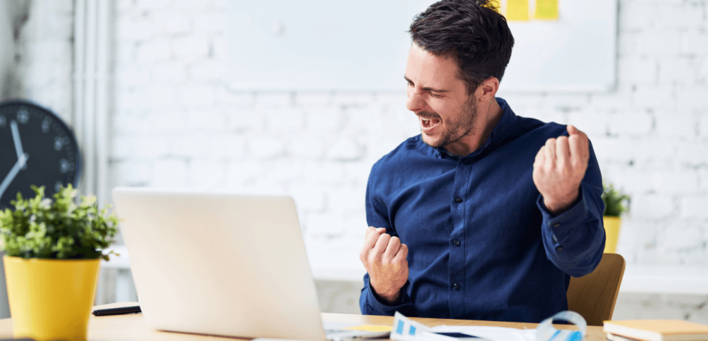 Man celebrating the outcome of a successful job interview at his desk