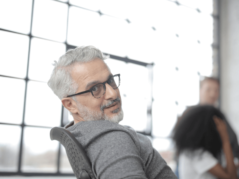 Employer questioning why bootcamps don't work. He looks inquisitively at the camera from his chair in front of a huge window