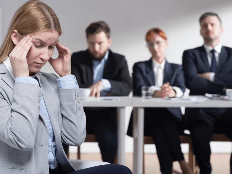 Lady holds her hands to her temples in front of the interview panel