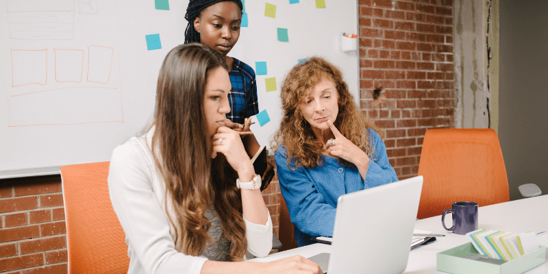 Colleagues helping young lady fix her mistakes after owning up to them