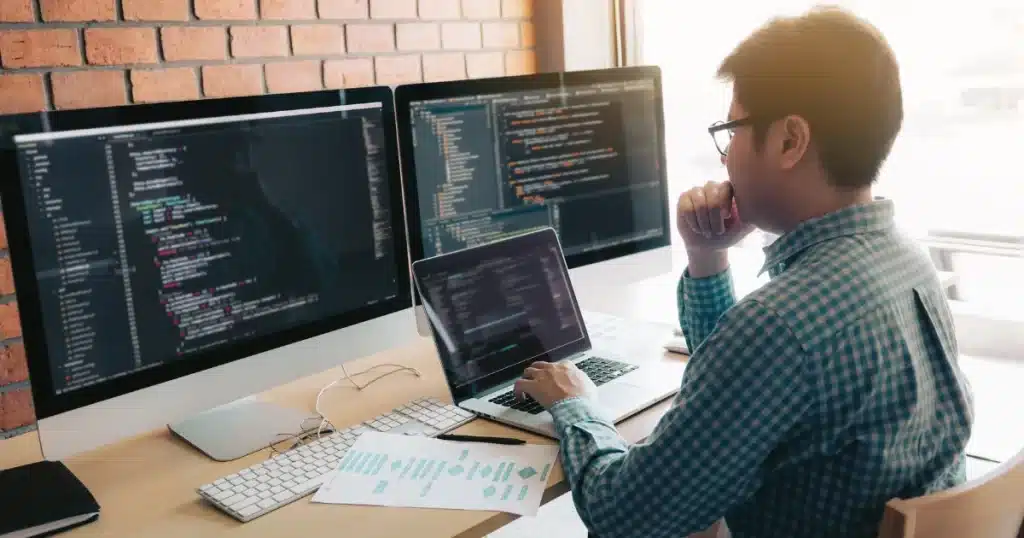 A young male software engineer writes code for a project