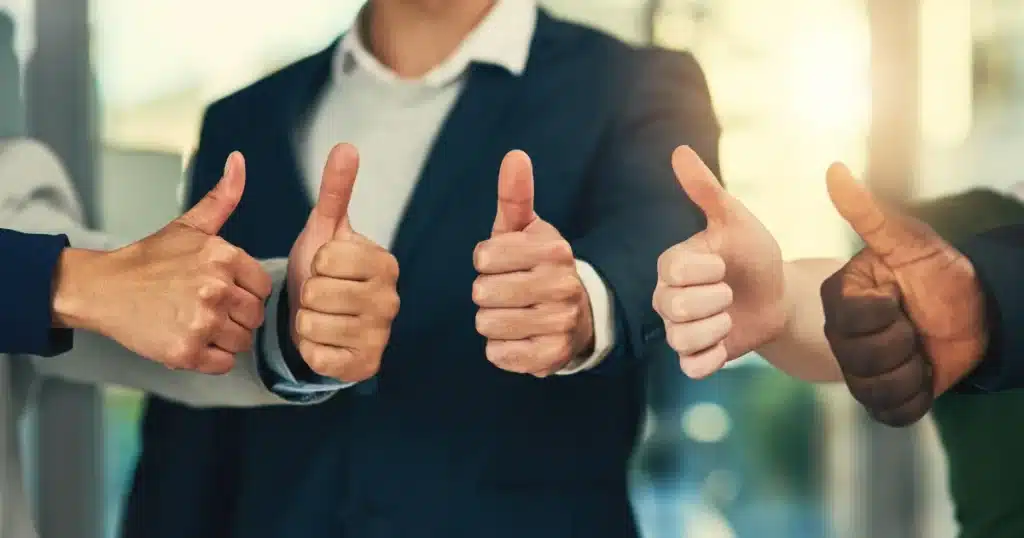 A group of diverse senior executives show their thumbs up to agree on the company mission and values