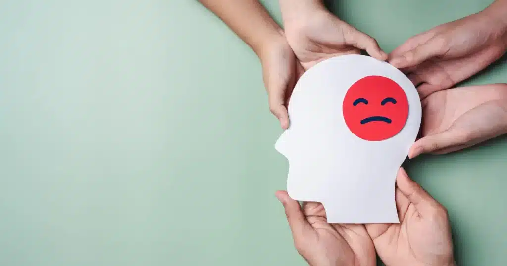 a few people hold together a head-shaped paper form with a worried face