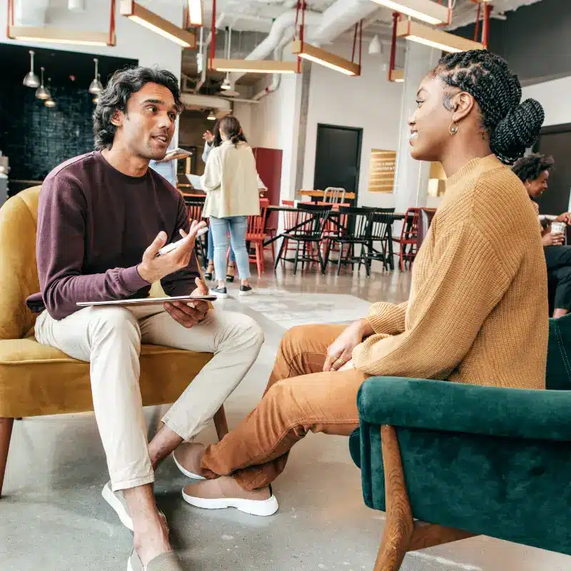 A hiring manager has an informal chat with a new hire in a relaxed environment in the office building