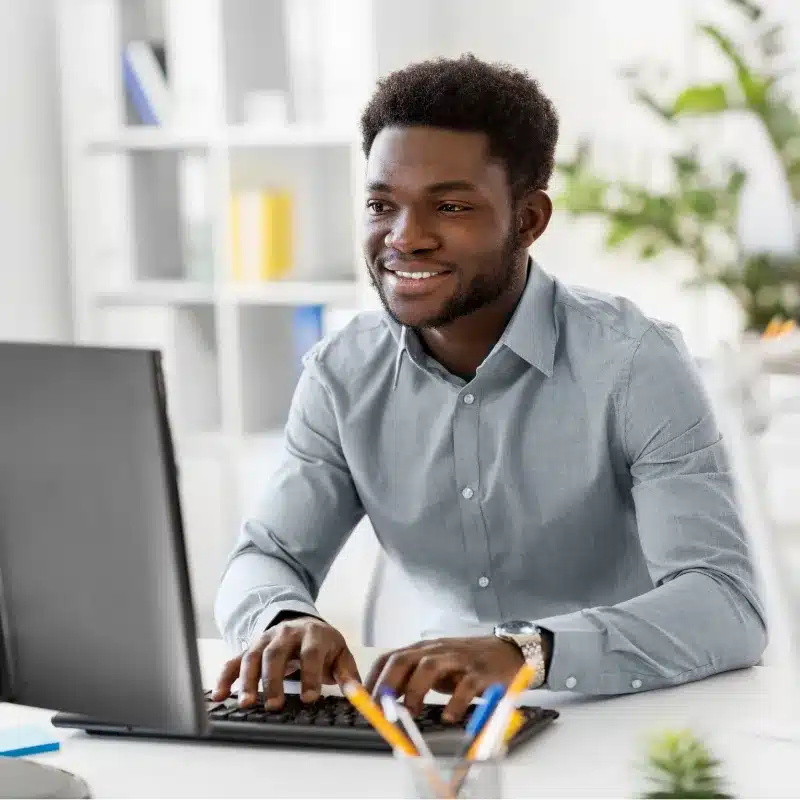 A black man smiles replying an email from a colleague