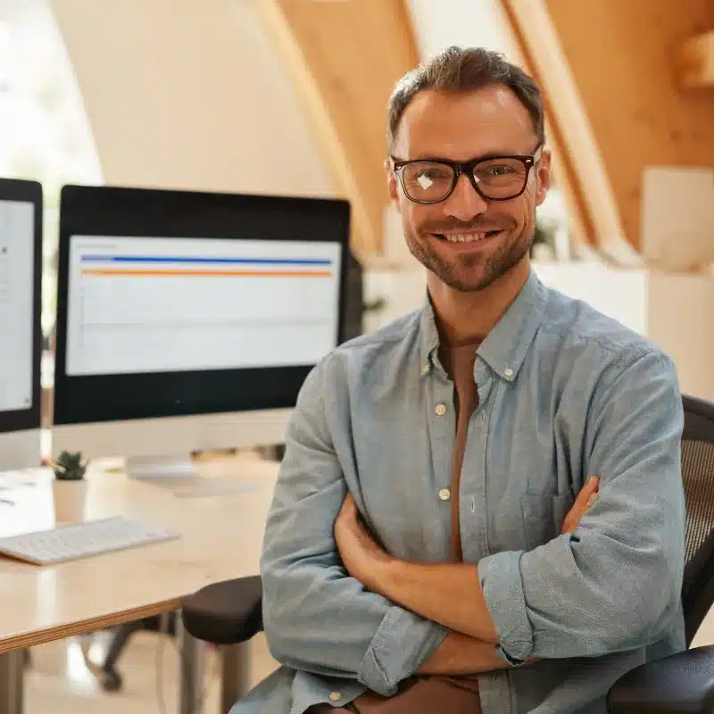 A marketing manager with glasses stands in his desk smile and confident