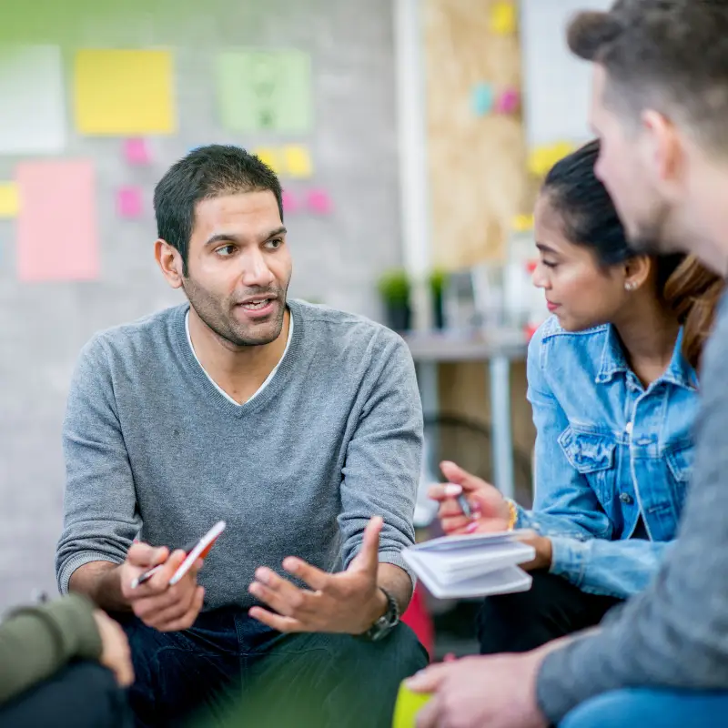 A marketing manager has a friendly chat with his team about a marketing campaign