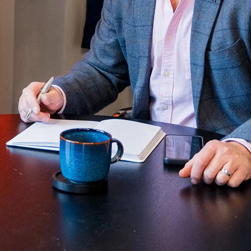 A senior recruitment consultant holds a notebook, ready to take notes in a meeting with a client