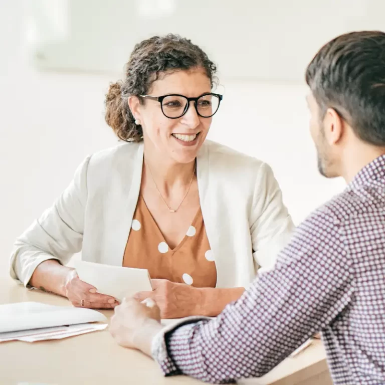 a woman with glasses in a smart look holds her interview notes while discussing a project at a job interview