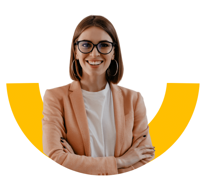A confident professional woman with glasses and a peach blazer smiling with arms crossed, standing in front of a yellow semi-circle graphic.