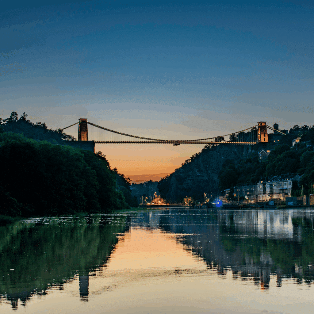 View of Clifton Suspension Bridge illuminated at sunset over the Avon Gorge in Bristol.