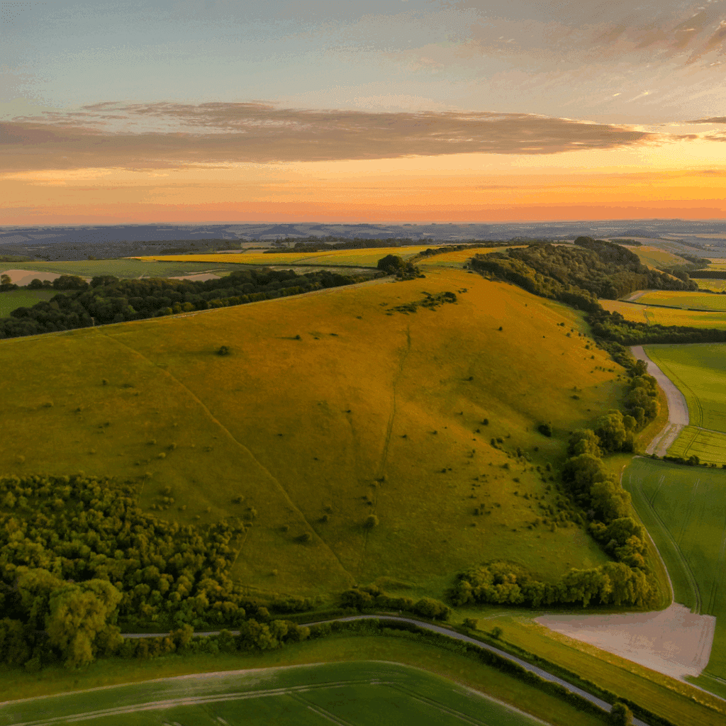 Aerial view of rolling green hills and countryside glowing in the warm light of sunset.