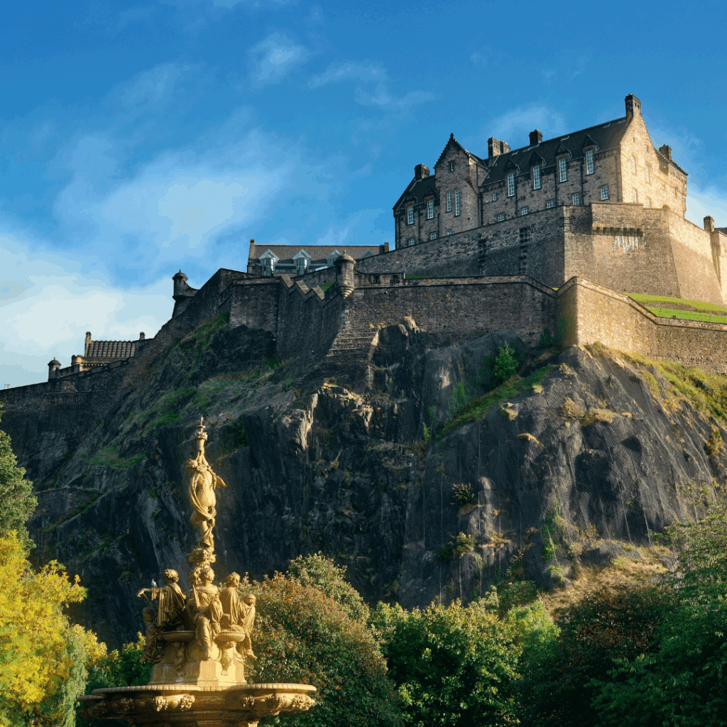 Edinburgh Castle perched atop Castle Rock on a clear day, with the Ross Fountain in the foreground.
