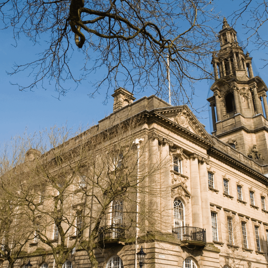 A grand neoclassical building in Preston, Lancashire, with bare trees and a clear blue sky, capturing the region's architectural heritage.