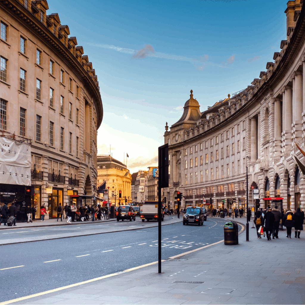 Curved façade of Regent Street bustling with cars, taxis, and pedestrians on a clear day