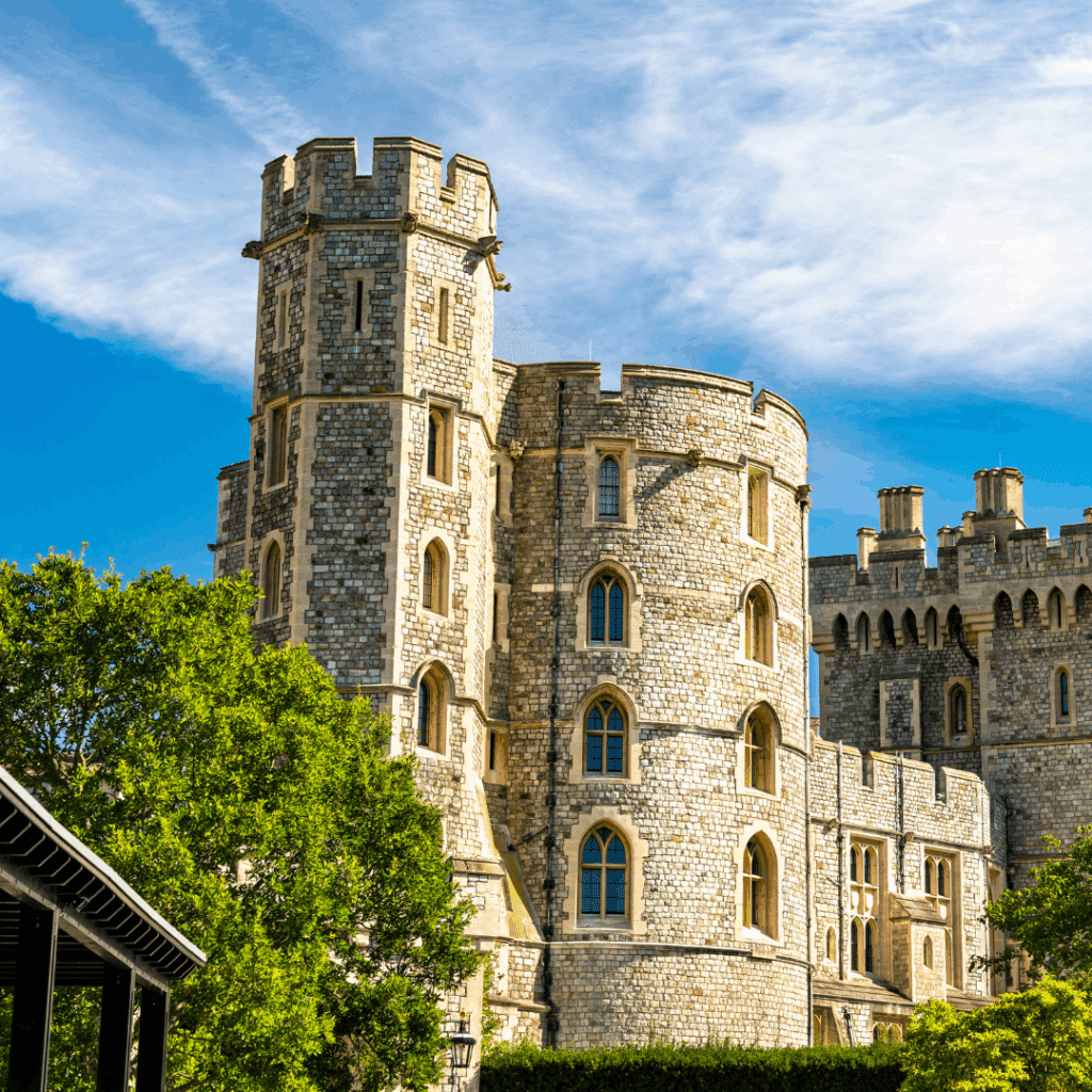 Close-up view of the stone towers and battlements of Windsor Castle against a blue sky.