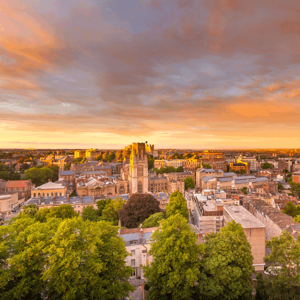 Aerial view of central Bristol with Wills Memorial Building lit by golden evening sunlight.