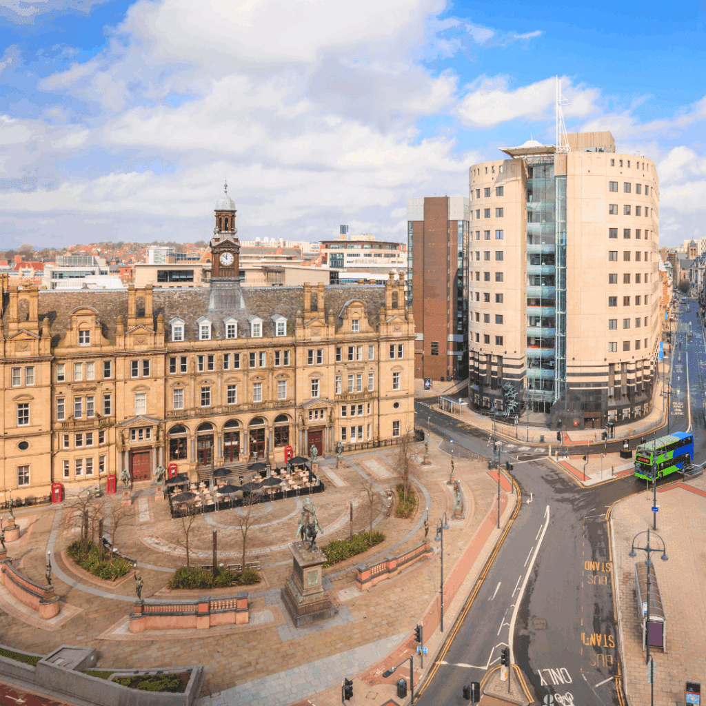 View of Leeds City Square featuring the old Post Office building, modern structures, and quiet streets under a blue sky.