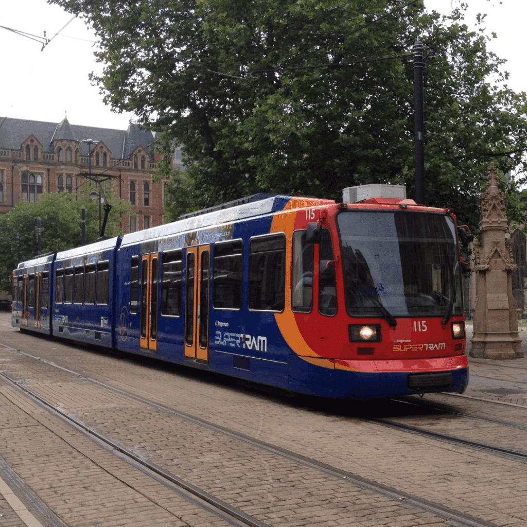 A Sheffield Supertram painted in blue and red travels through the city centre near Victorian buildings.