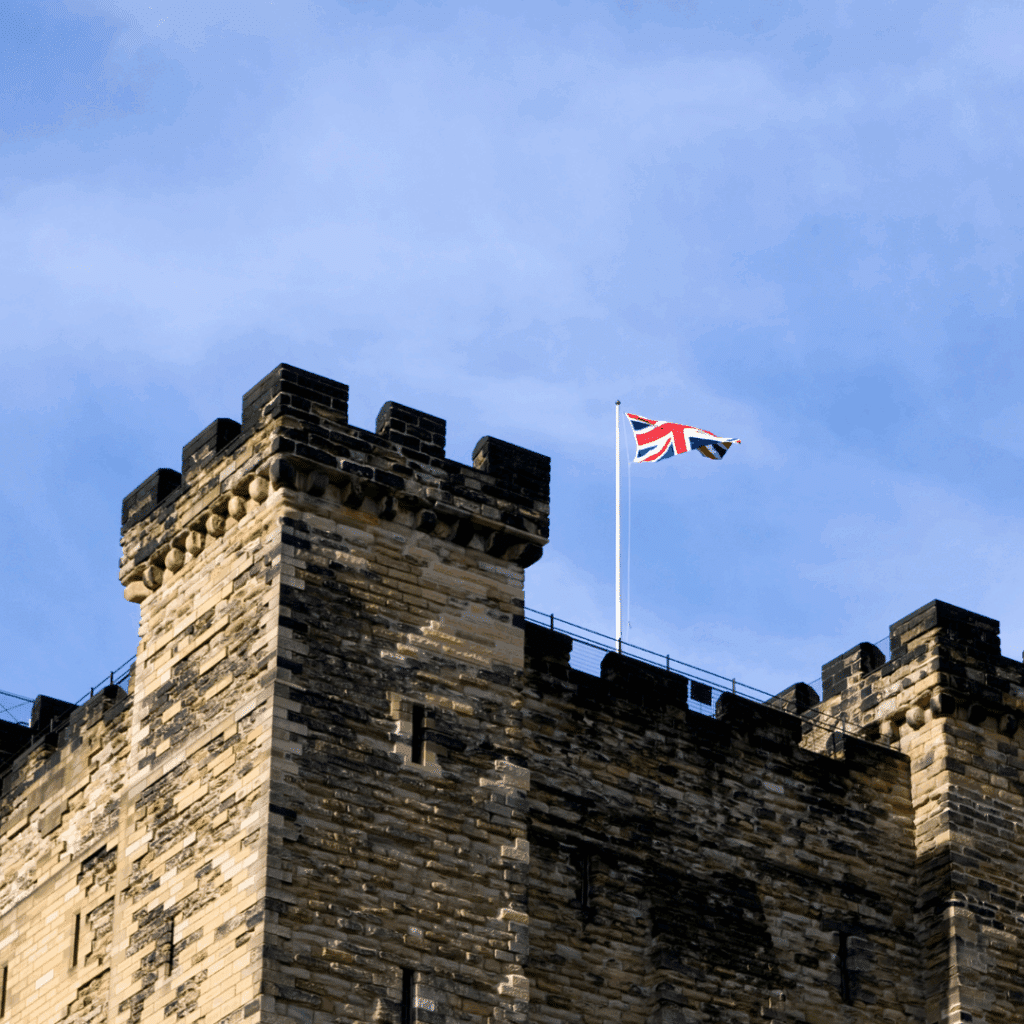 A stone turret of Newcastle Castle with a Union Jack flag flying above, symbolising the city's medieval heritage.
