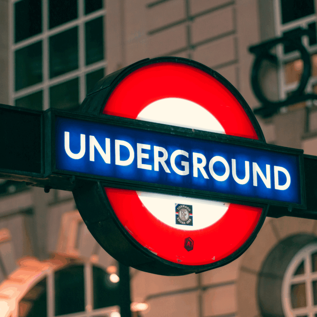 Close-up of the illuminated London Underground roundel outside a tube station in the evening