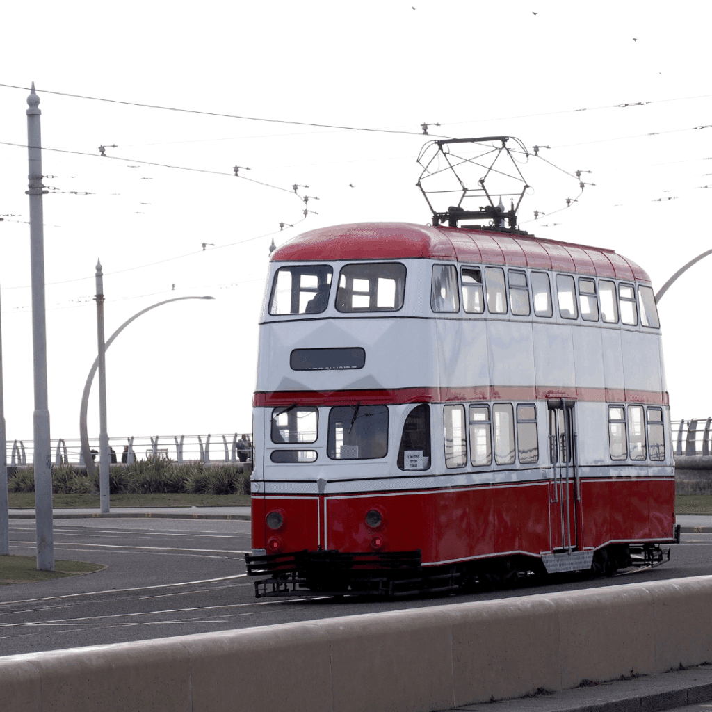 A classic red and white double-decker tram travelling along the seaside tracks in Blackpool, Lancashire.