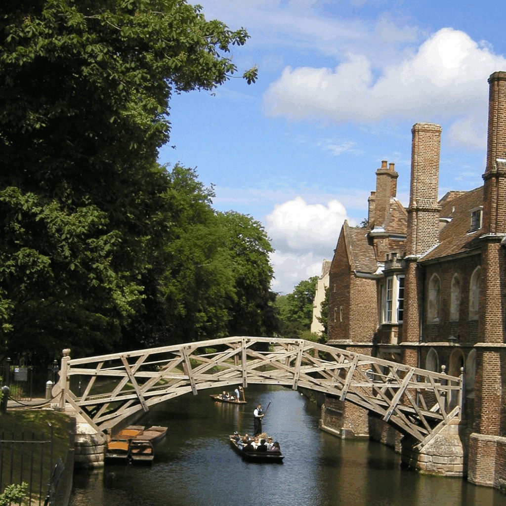 The Mathematical Bridge spans the River Cam at Queens' College, Cambridge, with punts and tourists passing beneath its wooden geometric structure.