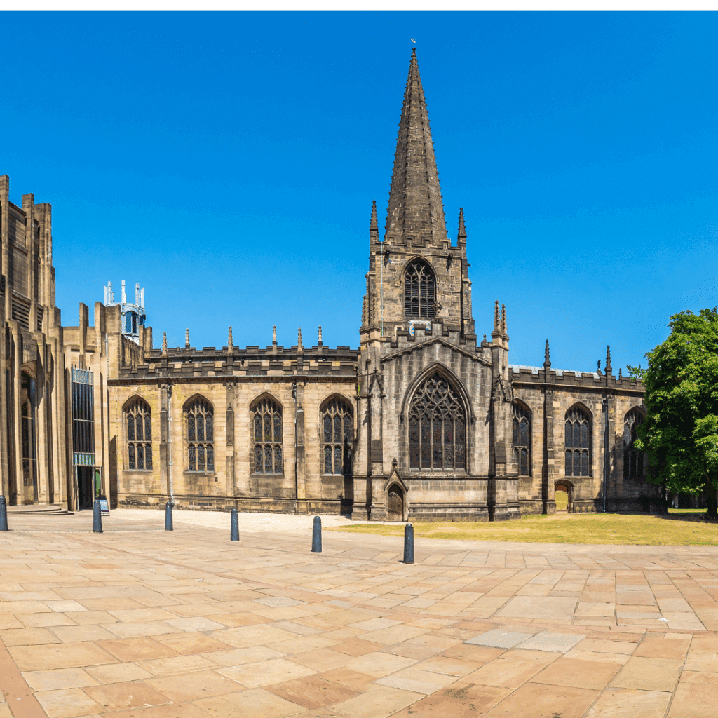 A wide view of Sheffield Cathedral with its gothic architecture and spire under a bright blue sky.