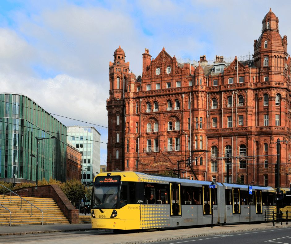 Tram travelling in front of the Midland Hotel in Manchester with a mix of modern and Victorian architecture in the background.

