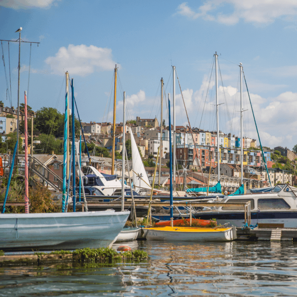 Boats docked in Bristol Marina with colorful hillside houses in the background.