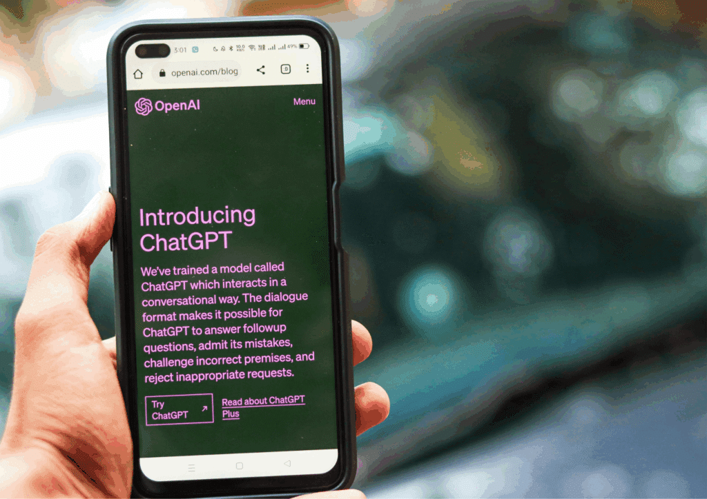 Close-up of a hand holding a smartphone with the ChatGPT introduction page from OpenAI open in the browser.