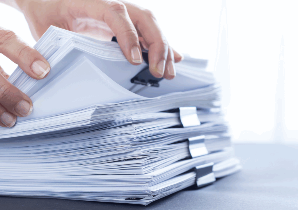 Close-up of hands organising a large stack of paper documents or printed resumes using binder clips, symbolising high application volume or administrative processing.