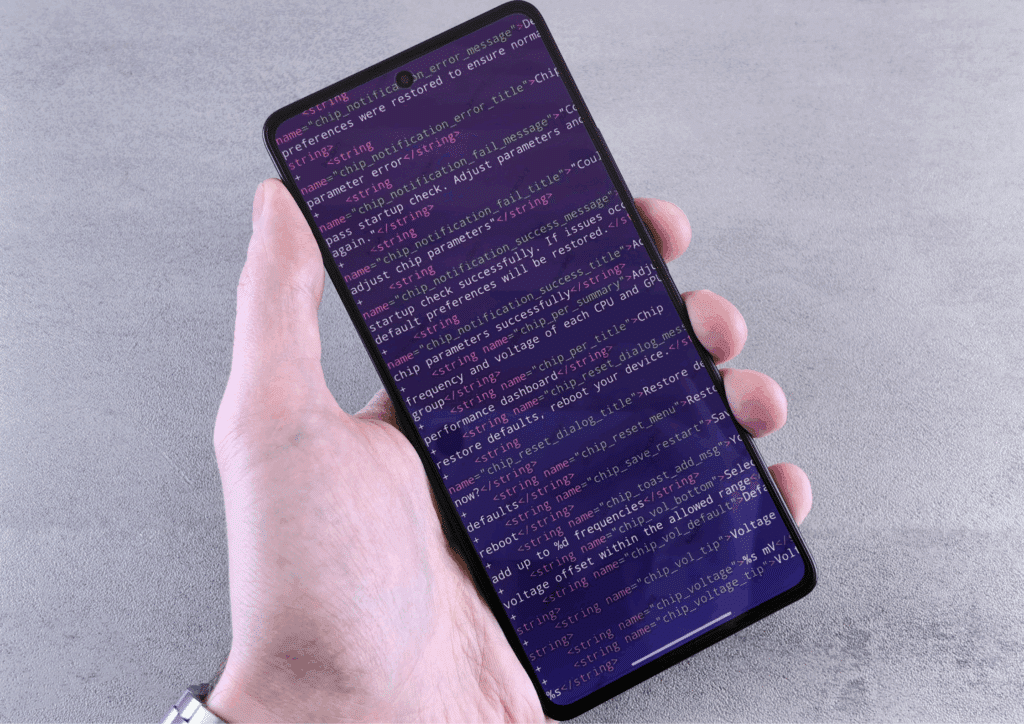 A hand holding a smartphone showing lines of code on the screen