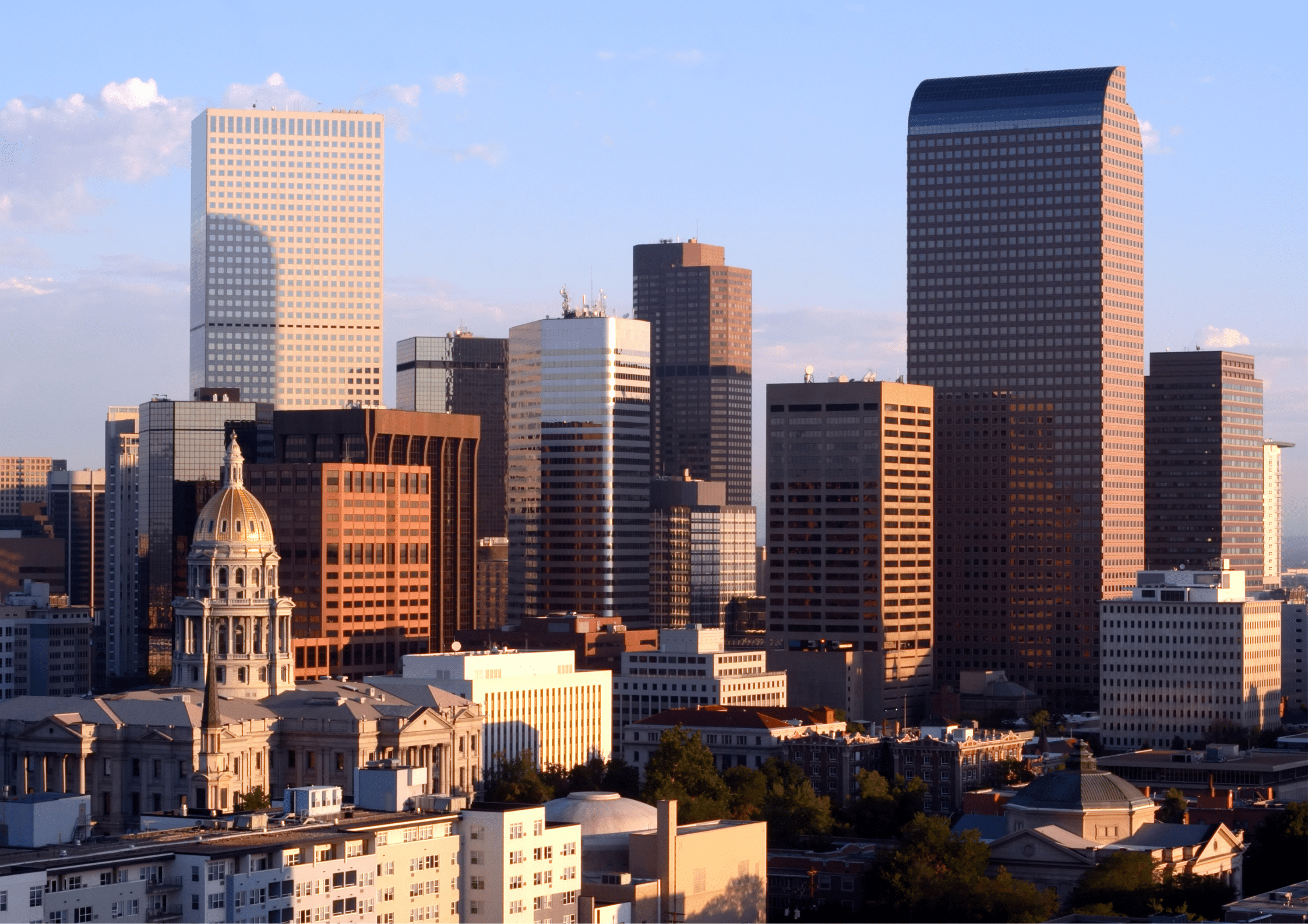 Denver skyline with mountain backdrop and historic capitol building in the foreground.