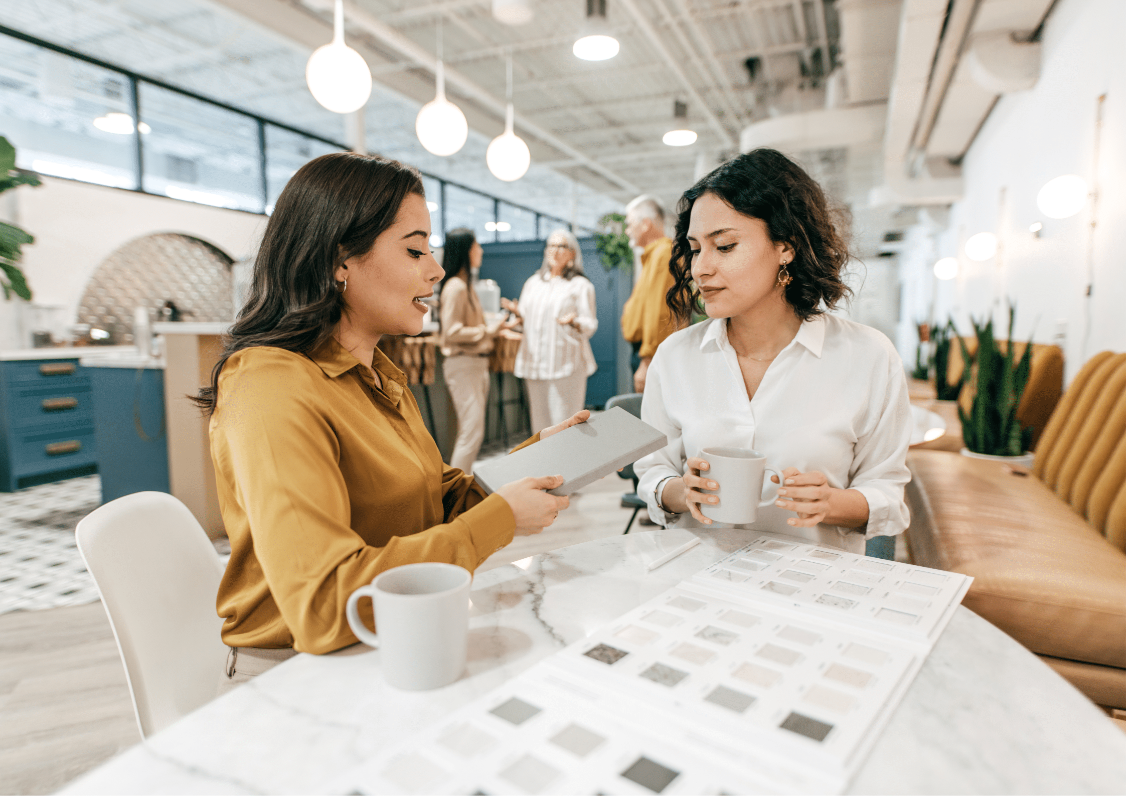 Two professionals discussing ideas over coffee and work materials in a modern office.