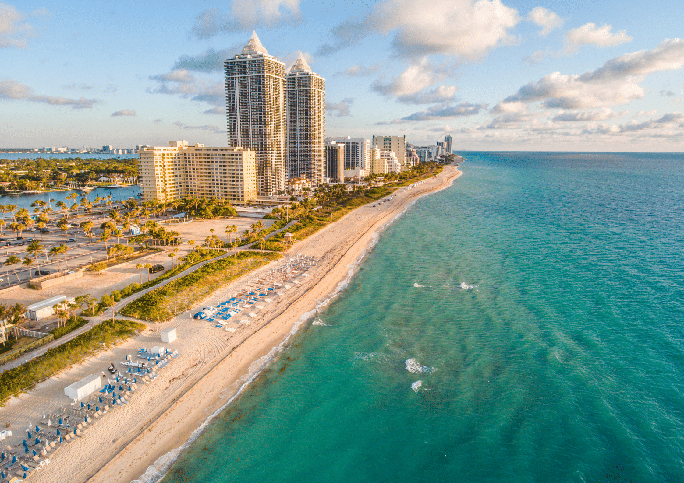 Aerial view of Miami beachfront high-rises with turquoise ocean and sandy shoreline.