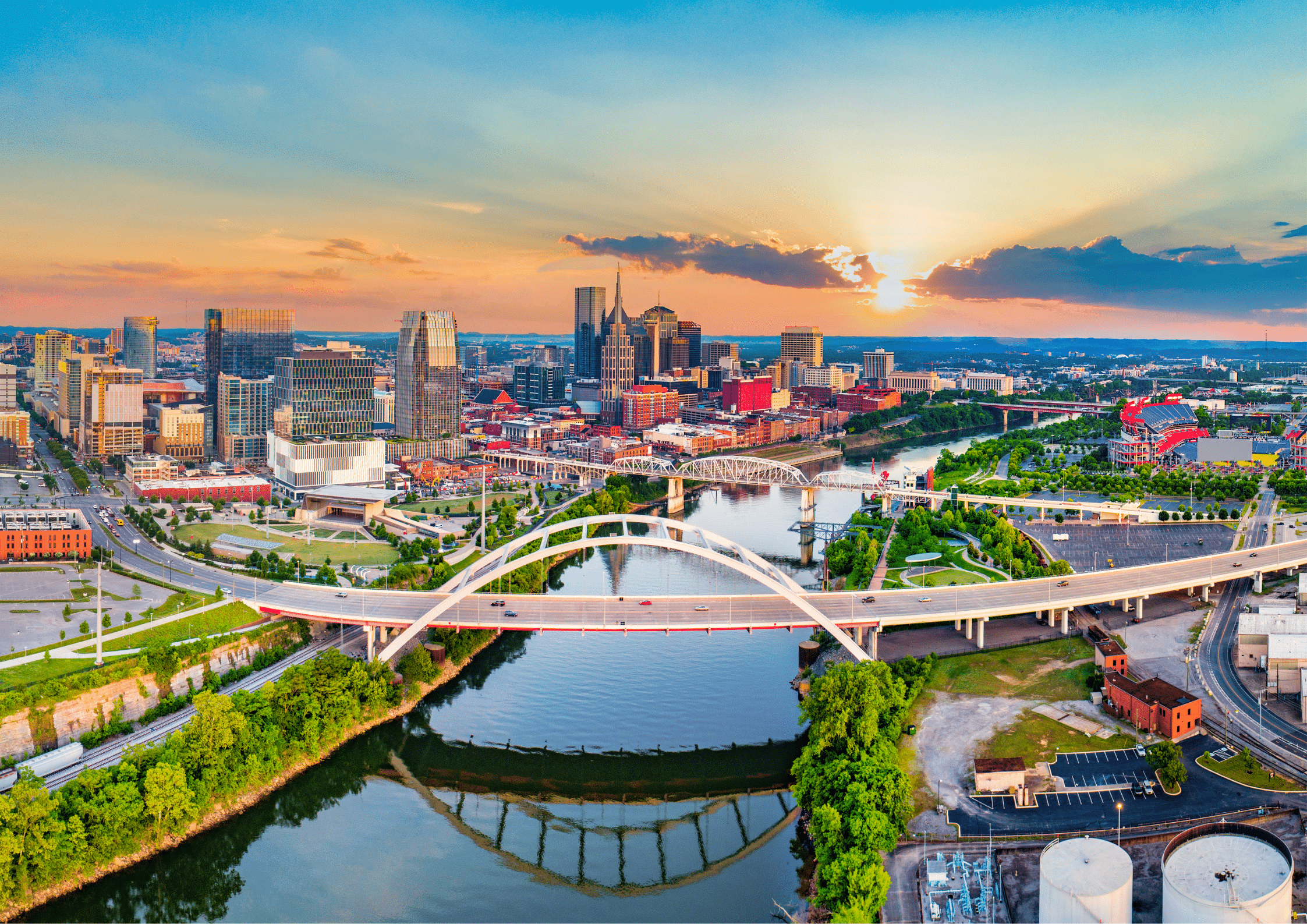 Aerial view of downtown Nashville skyline and bridge at sunset.