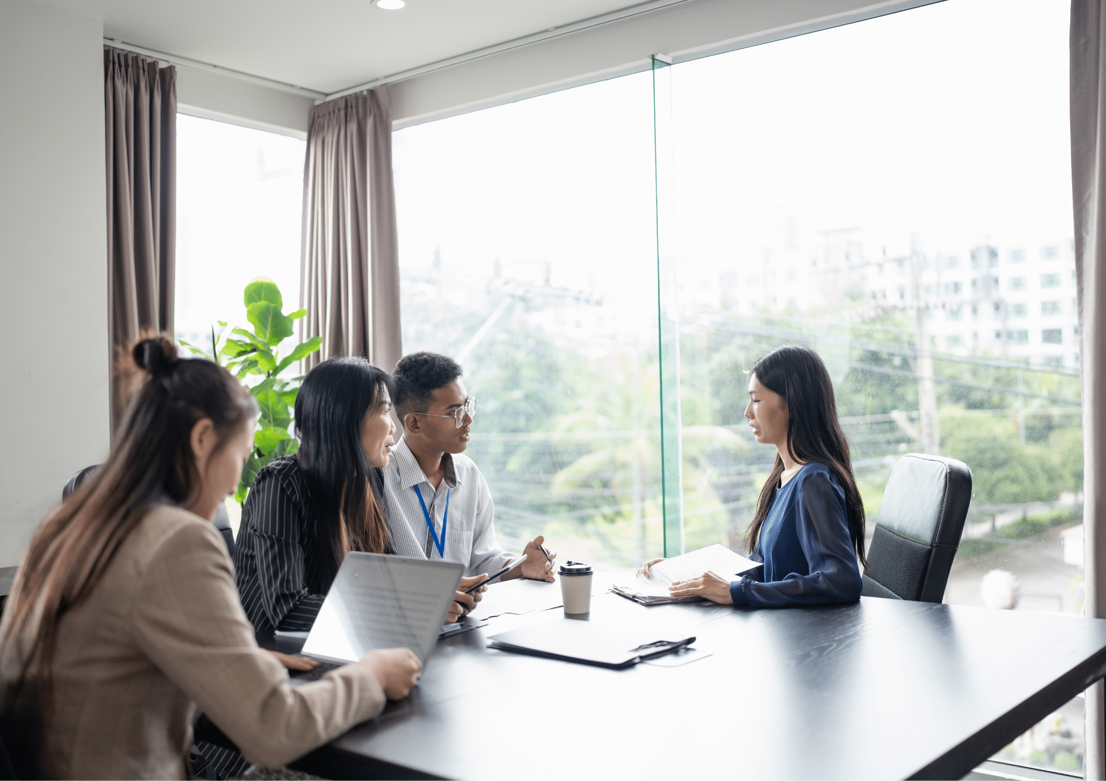 A group of professionals sit around a table conducting a job interview, reviewing documents and discussing role requirements in a modern office.