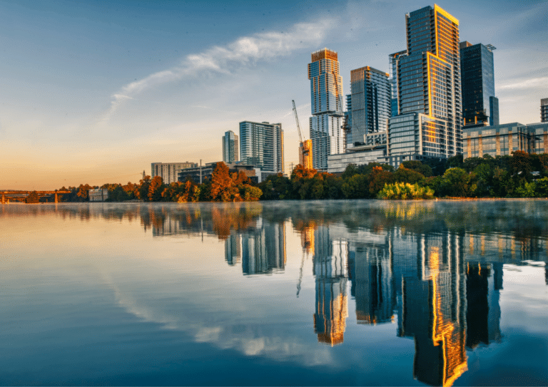 Modern high rise buildings in Austin, Texas reflected in calm water at sunrise.