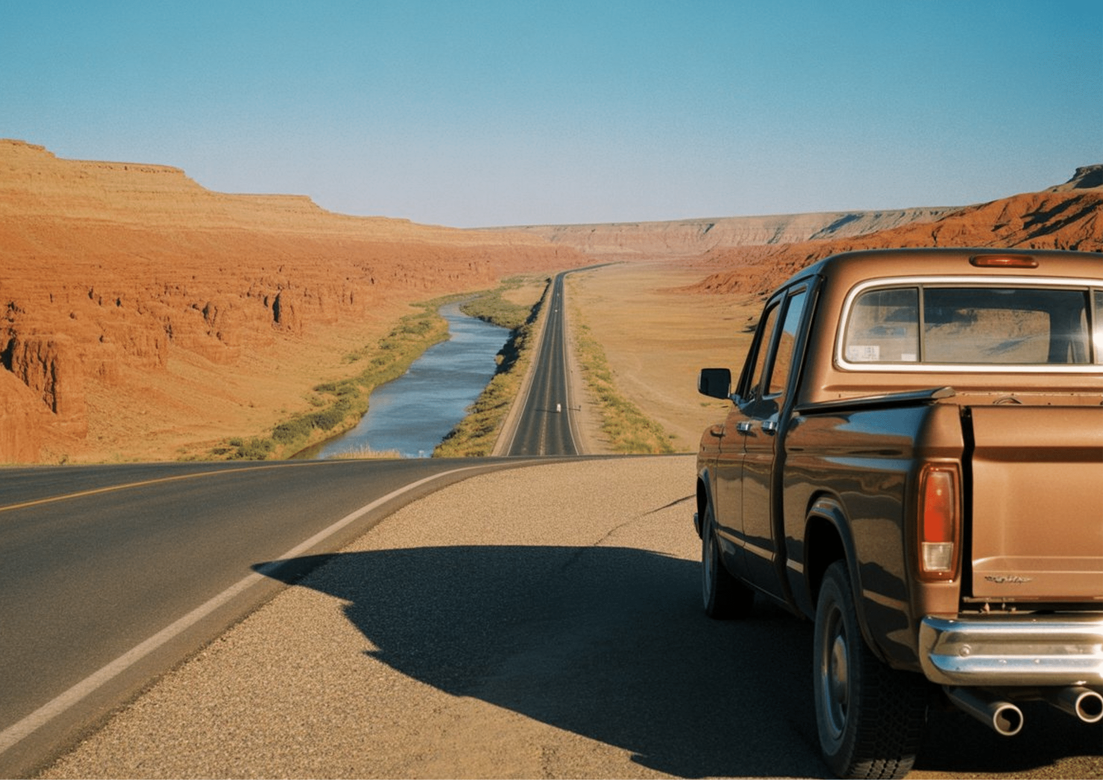Brown pickup truck driving along a long desert highway with red rock landscape and river in Texas.