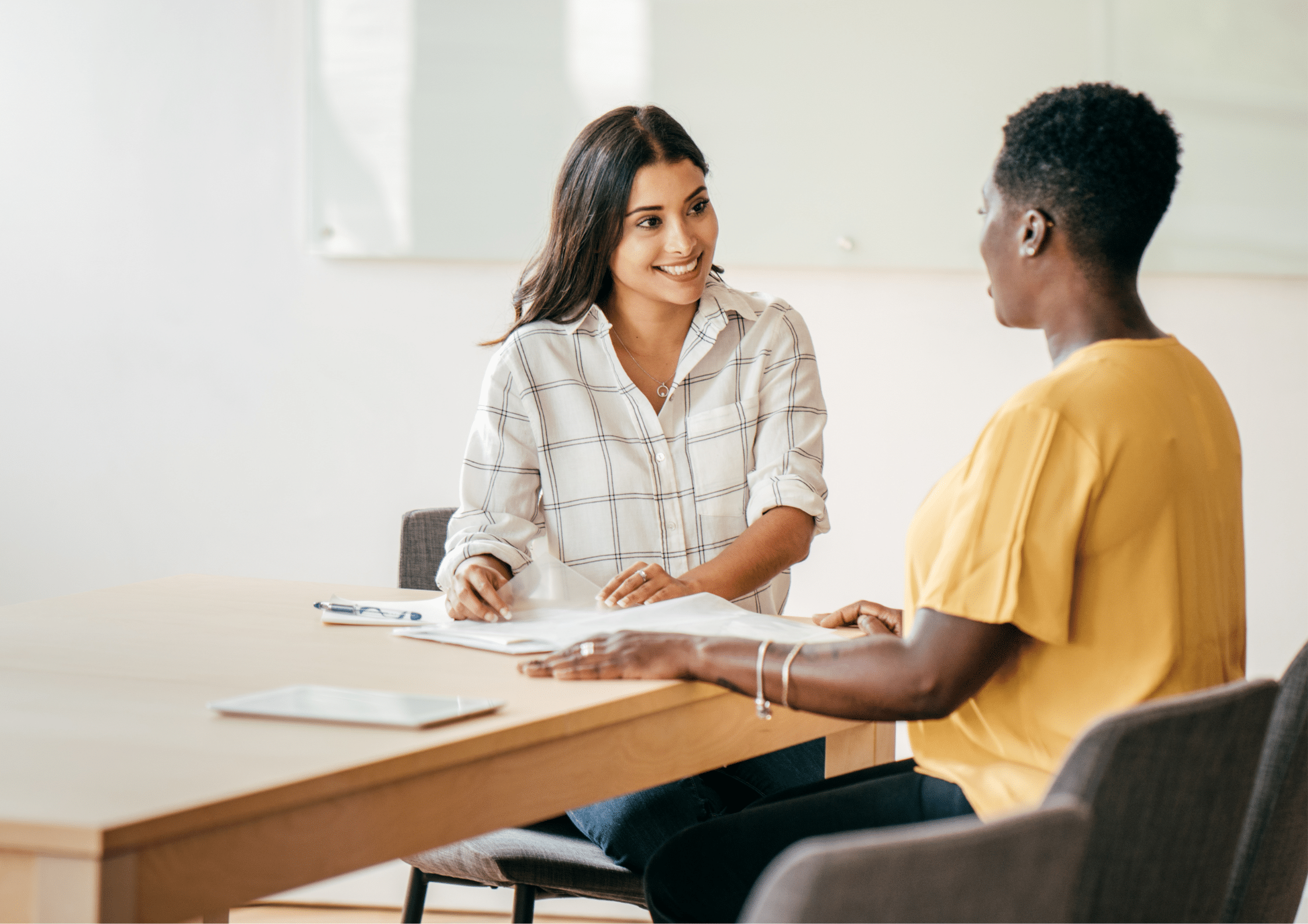 Two women discussing job opportunities in an office meeting